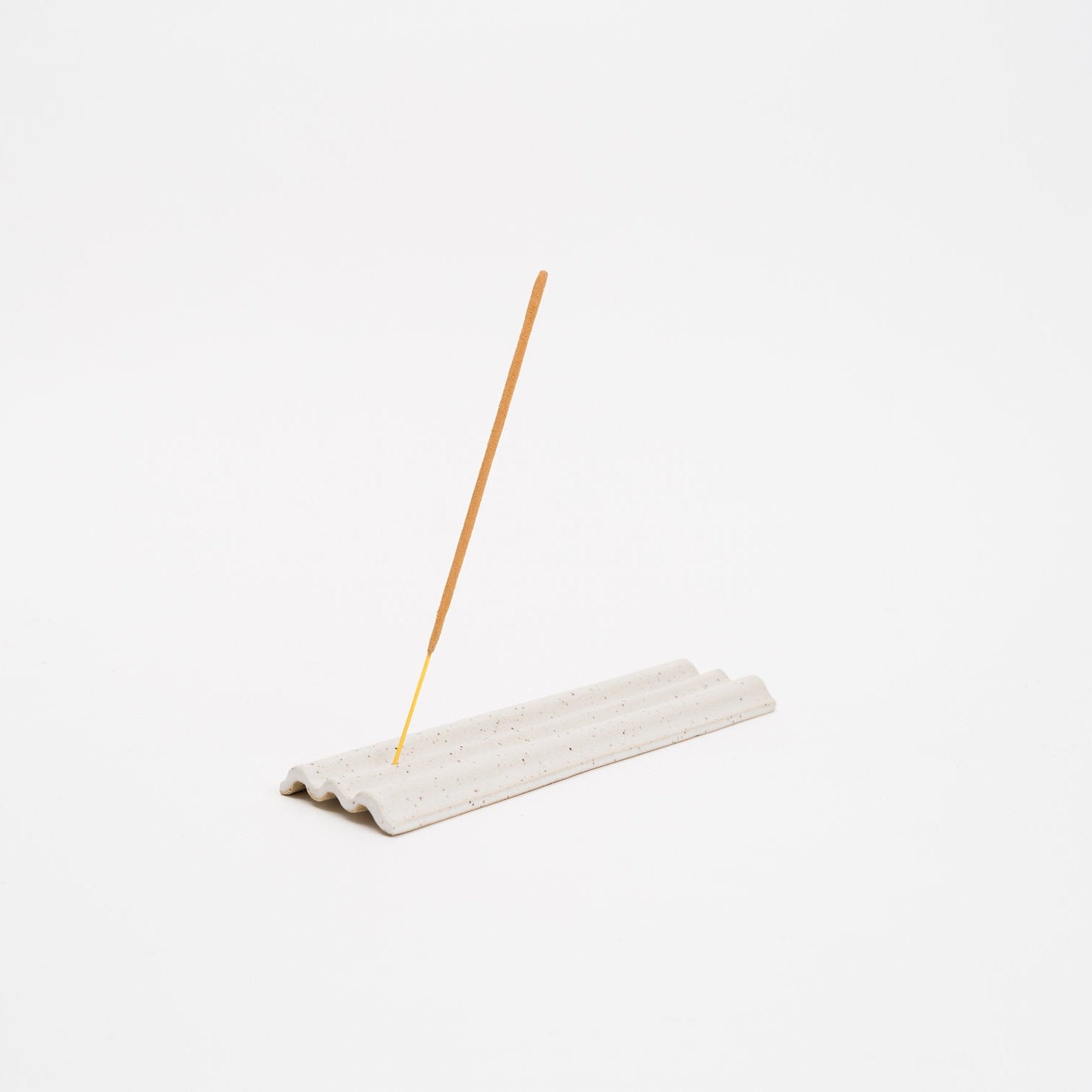 Incense stick on a white stone holder against a white background